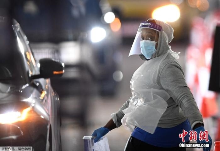 當(dāng)?shù)貢r(shí)間12月18日，英國(guó)政府公布的數(shù)據(jù)顯示，當(dāng)天英國(guó)新增奧密克戎毒株感染病例10059例。鑒于奧密克戎毒株感染病例激增，住院人數(shù)不斷上升，倫敦市長(zhǎng)宣布倫敦進(jìn)入“重大事故”狀態(tài)。圖為倫敦的一個(gè)免下車檢測(cè)中心，一名醫(yī)務(wù)工作者正準(zhǔn)備對(duì)司機(jī)進(jìn)行核酸檢測(cè)。