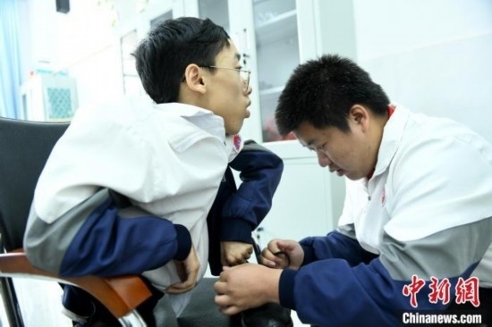 江西省南康中學(xué)北校區(qū)的高三學(xué)生朱金祥(右)正在給鐘華強(qiáng)(左)系好鞋帶。 卓忠偉 攝