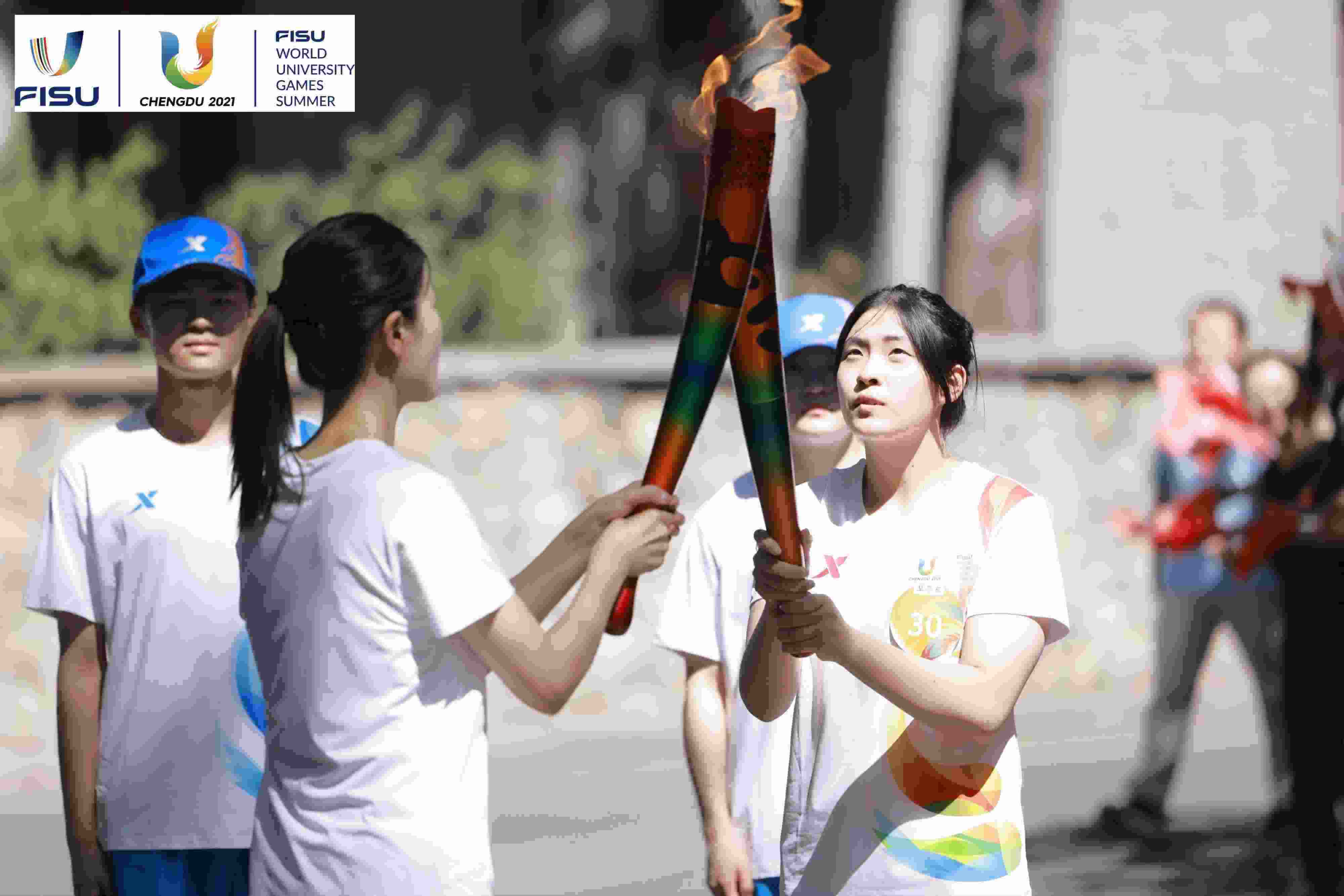 兩名大運(yùn)會(huì)火炬手進(jìn)行火炬?zhèn)鬟f。 圖片來源：成都大運(yùn)會(huì)執(zhí)委會(huì)供圖