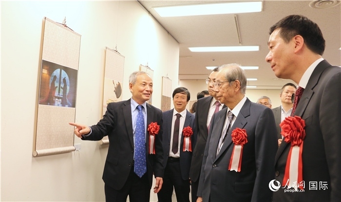 “湖州印象”攝影展主創(chuàng)、世界華人攝影協(xié)會副會長馮學敏向吳江浩大使、福田康夫前首相等嘉賓介紹展出作品。（人民網(wǎng) 許可攝）