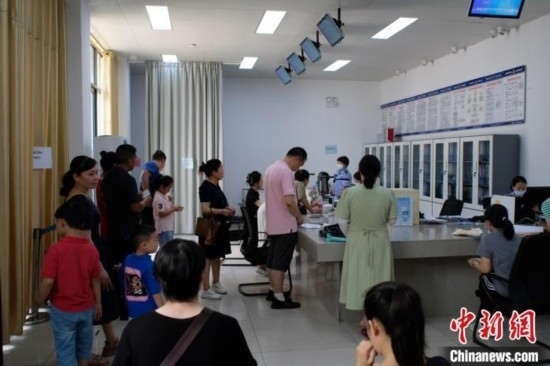 圖為在戶籍辦證廳內(nèi)排隊(duì)等待的家長和孩子。劉俊聰 攝