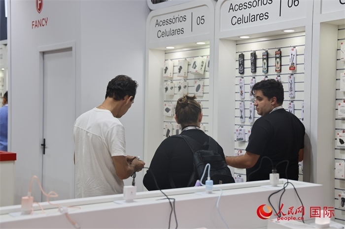 幾名參觀者在一個展臺前了解手機配件。（人民網(wǎng)記者 時元皓攝）