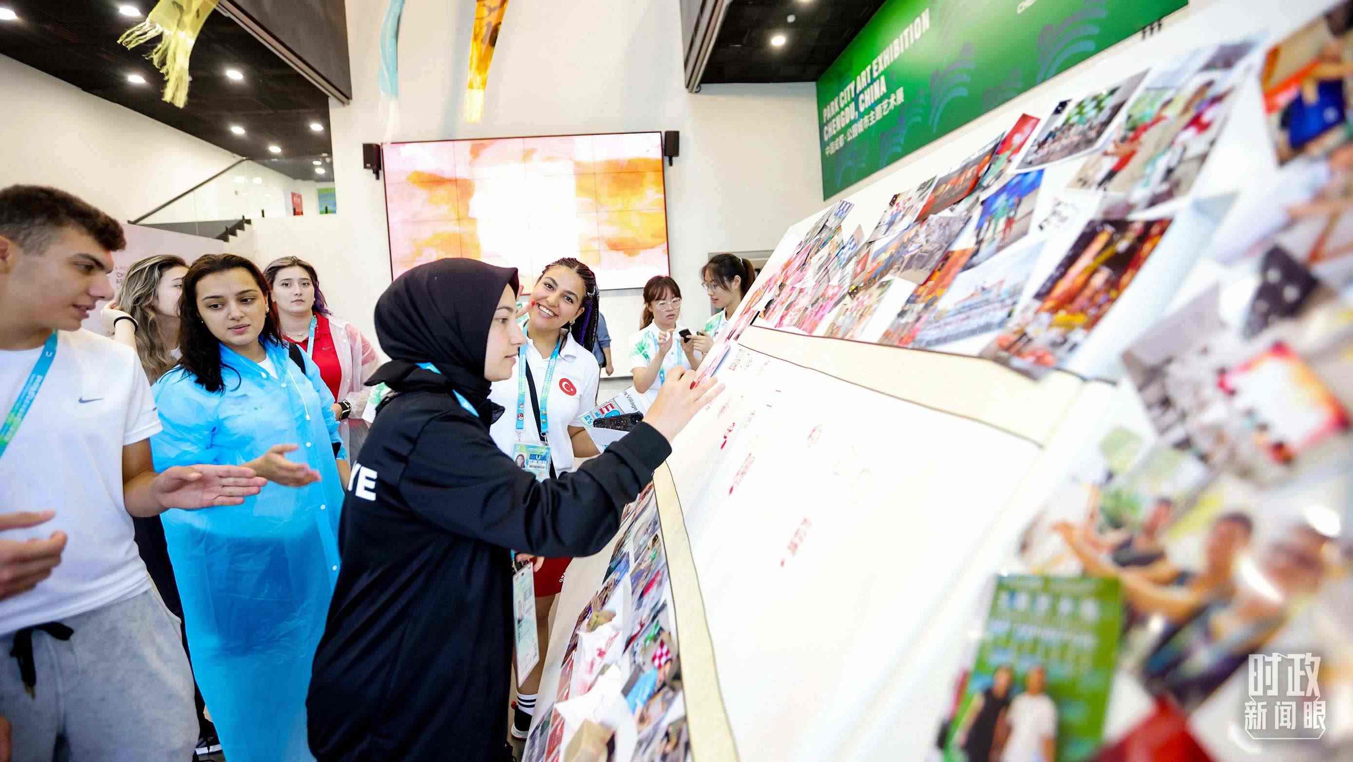 各國青年運(yùn)動(dòng)員正在參觀成都大運(yùn)村內(nèi)的“雪山下的公園城市，煙火里的幸福成都”主題藝術(shù)展。（總臺(tái)央視記者魏幫軍拍攝）