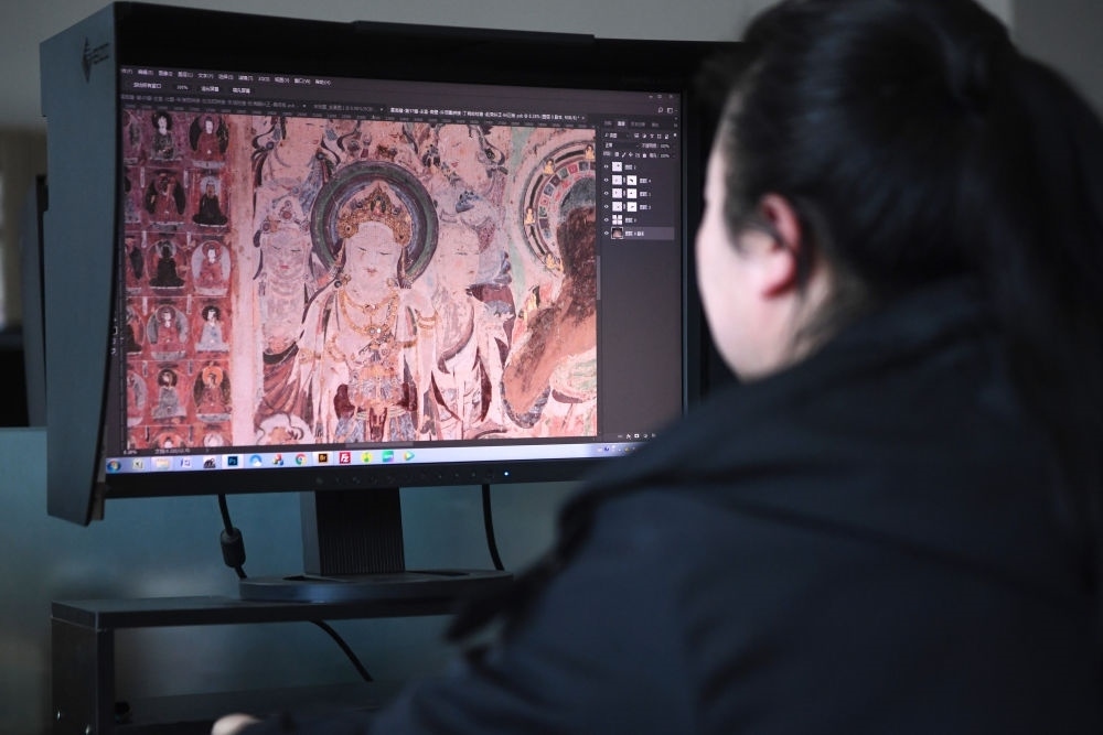 敦煌研究院文物數(shù)字化保護(hù)團(tuán)隊(duì)圖像處理人員年海麗在拼接壁畫(huà)圖像（2023年4月25日攝）。數(shù)字化探索為莫高窟的保護(hù)與傳承開(kāi)辟了全新路徑，數(shù)字技術(shù)讓敦煌文物走出洞窟，跨出國(guó)門(mén)，走向“永久保存、永續(xù)利用”。新華社記者 陳斌 攝
