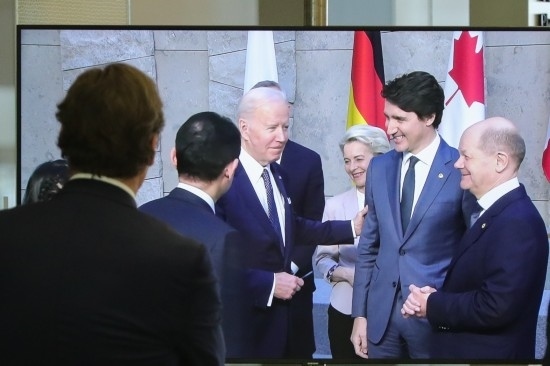 2022年3月24日，在比利時(shí)布魯塞爾的北約總部，一名男子觀看屏幕上美國(guó)總統(tǒng)拜登（右四）、歐盟委員會(huì)主席馮德萊恩（右三）、加拿大總理特魯多（右二）、德國(guó)總理朔爾茨（右一）出席七國(guó)集團(tuán)峰會(huì)合影儀式的畫(huà)面。新華社記者鄭煥松攝