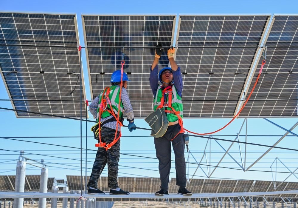 2023年7月22日，工人在位于內(nèi)蒙古杭錦旗庫布其沙漠億利生態(tài)示范區(qū)的蒙西基地庫布其200萬千瓦光伏治沙項目工地安裝光伏板。新華社記者 劉磊 攝