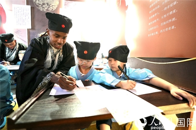 圖為選手與同學(xué)們一起寫(xiě)書(shū)法。人民網(wǎng) 盧鵬宇攝