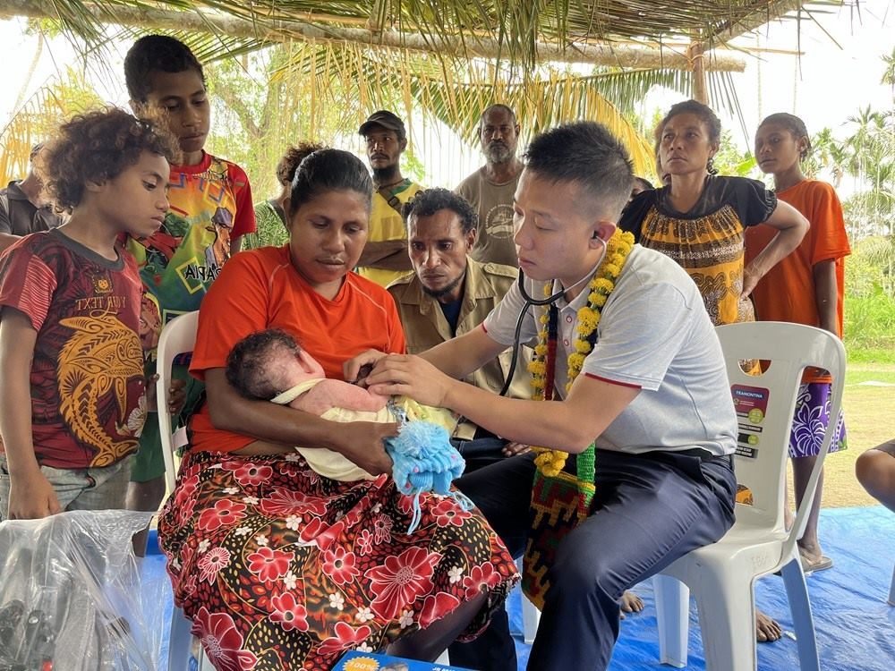 2023年8月5日，在巴布亞新幾內(nèi)亞中央省的一個(gè)村莊里，第12批援巴新中國醫(yī)療隊(duì)副隊(duì)長、新生兒科副主任醫(yī)師劉振球?yàn)楫?dāng)?shù)貗雰郝犜\檢查。新華社發(fā)（第12批援巴新中國醫(yī)療隊(duì)供圖）