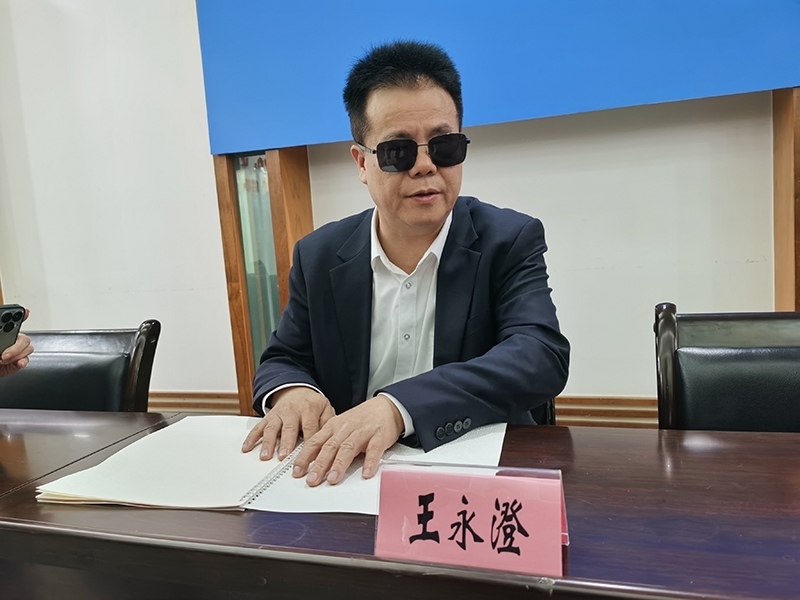 全國人大代表王永澄正在閱讀盲文版代表建議答復(fù)。本報記者 張 璁?dāng)z