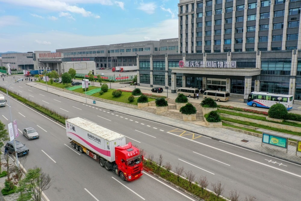 2023年10月11日，滿載筆記本電腦配件、發(fā)電機(jī)組件等產(chǎn)品的西部陸海新通道跨境公路班車從重慶南彭公路保稅物流中心駛出，將途經(jīng)廣西憑祥，直達(dá)越南（無人機(jī)照片）。新華社記者 黃偉 攝