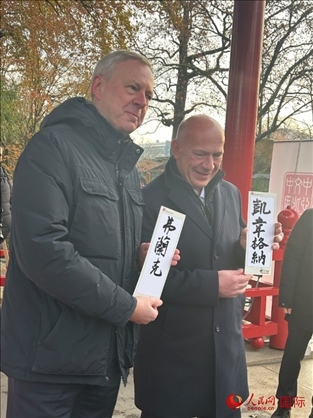 柏林市長韋格納（右）、動物園監(jiān)事會主席布魯克曼（左）手持中國文化中心工作人員現(xiàn)場手書的中文名字。人民網(wǎng)記者 徐馨攝