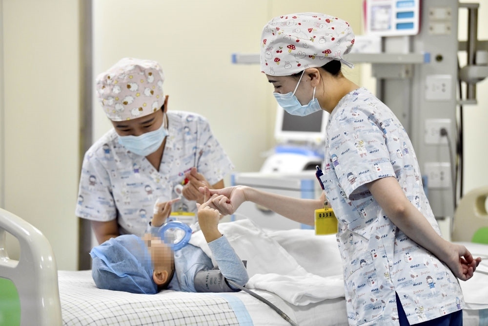 在山東省棗莊市婦幼保健院兒童ICU病房，醫(yī)護(hù)人員為完成靶向治療藥物諾西那生鈉的4歲脊髓性肌萎縮癥患兒加油鼓勁（2022年1月1日攝）。諾西那生鈉注射液是我國首個獲批治療脊髓性肌萎縮癥的進(jìn)口藥物，2019年進(jìn)入中國市場時，每針價格近70萬元。在2021年國家醫(yī)保目錄藥品談判中，以3.3萬元每針的價格進(jìn)入新版醫(yī)保藥品目錄。新華社記者 郭緒雷 攝