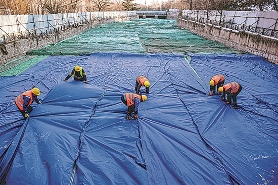 1月3日，房山區(qū)東風(fēng)街道，工人正在修復(fù)的河道內(nèi)給混凝土鋪設(shè)保溫布。