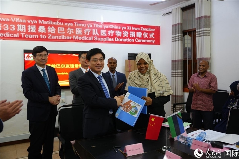 江蘇省蘇北人民醫(yī)院黨委書記束余聲與桑衛(wèi)生部首席秘書哈比巴交換捐贈(zèng)書。中國(guó)援桑醫(yī)療隊(duì)供圖