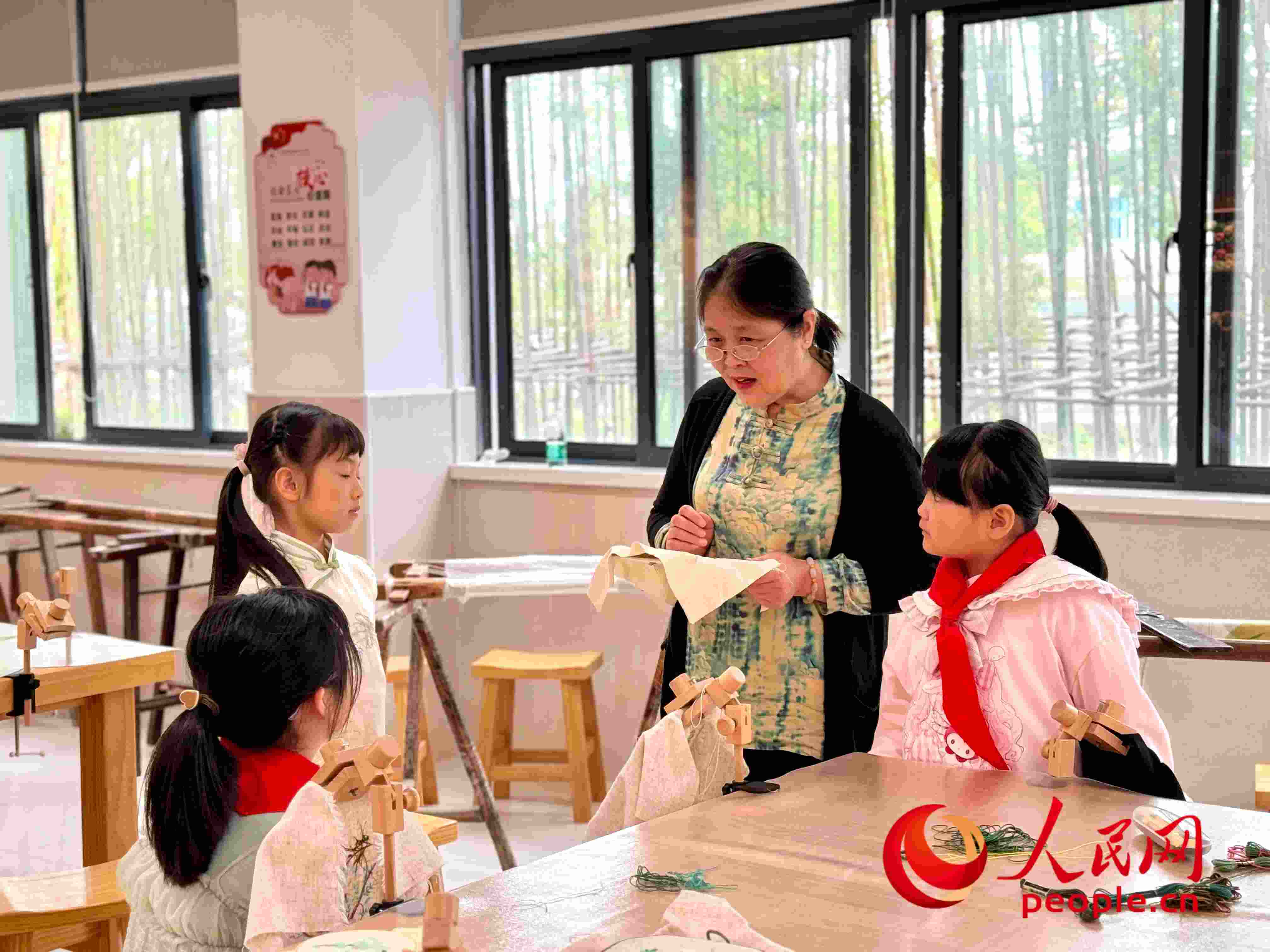 顧建珍（左三）在教孩子們刺繡知識(shí)。人民網(wǎng) 周靜圓攝