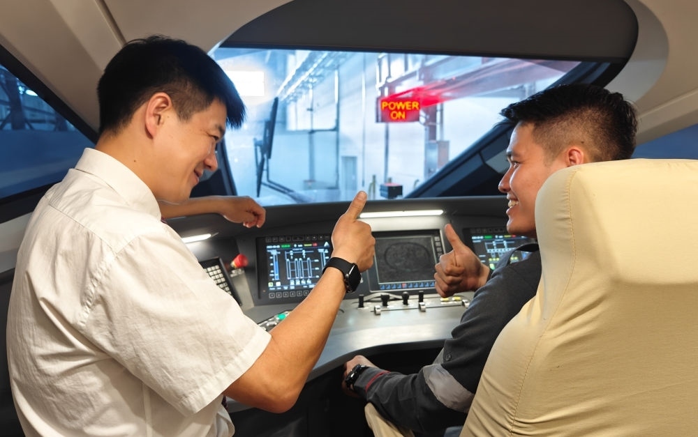 2023年8月25日，在印度尼西亞萬隆的雅萬高鐵德卡魯爾動車所內(nèi)，中國師傅穆振（左）向印尼火車司機(jī)塞蒂亞萬講解動車組出庫前的上電作業(yè)。新華社記者 徐欽 攝