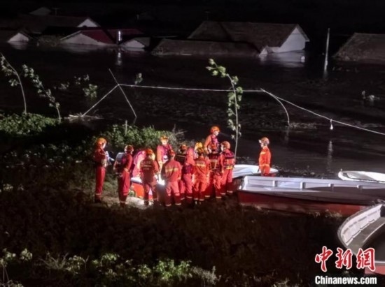  7月6日凌晨3時，在湖南岳陽華容縣團洲垸洞庭湖一線堤防，救援人員剛剛完成一次救援任務(wù)，遠處是被淹的民房。中新社記者 白祖偕 攝