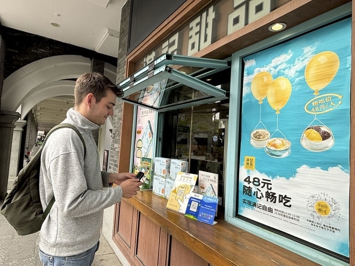 來自德國的留學(xué)生理查德在杭州西湖邊一家商鋪使用支付寶掃碼支付（2024年4月11日攝）。新華社發(fā)