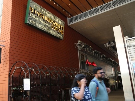 2023年5月29日，人們經(jīng)過美國紐約曼哈頓的“國債鐘”。“國債鐘”是一個(gè)大型計(jì)數(shù)器，它實(shí)時(shí)更新美國的公共債務(wù)總額，并顯示出每個(gè)美國家庭所要負(fù)擔(dān)的數(shù)額。 新華社記者劉亞南攝