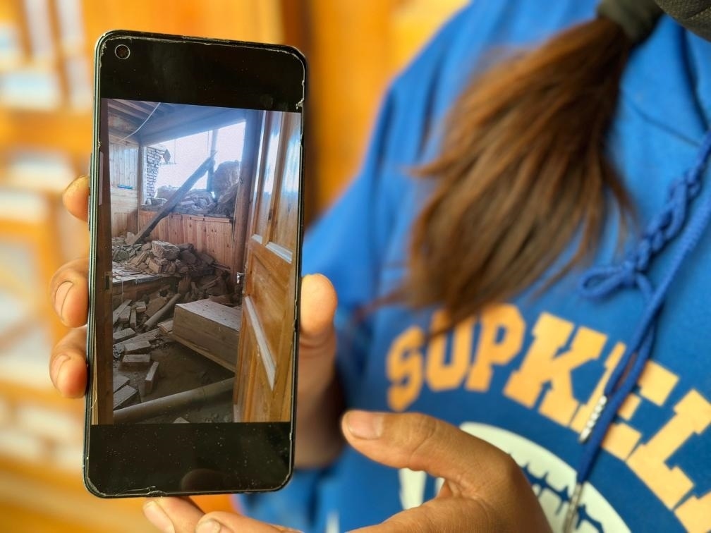 圖為7月17日拉毛東智在手機(jī)上找出地震后房屋受損的照片。新華社記者 張子琪 攝