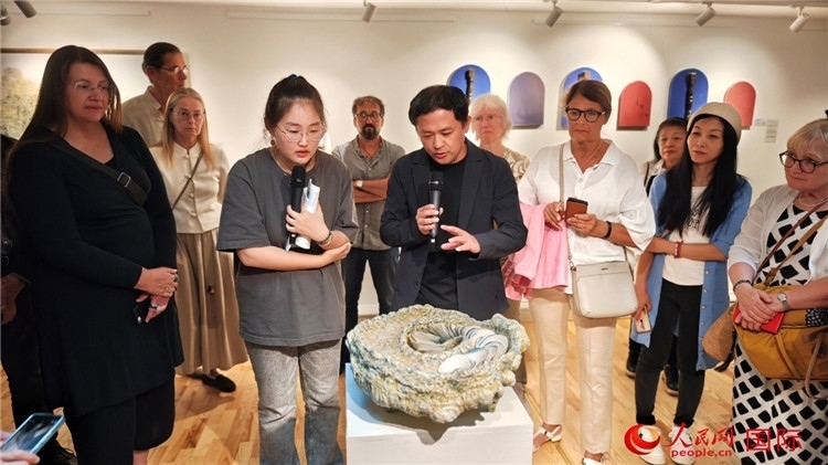 參展人、景德鎮(zhèn)陶瓷大學(xué)設(shè)計(jì)藝術(shù)學(xué)院副院長(zhǎng)余劍峰（中）向來(lái)賓介紹參展作品。人民網(wǎng)記者 殷淼攝