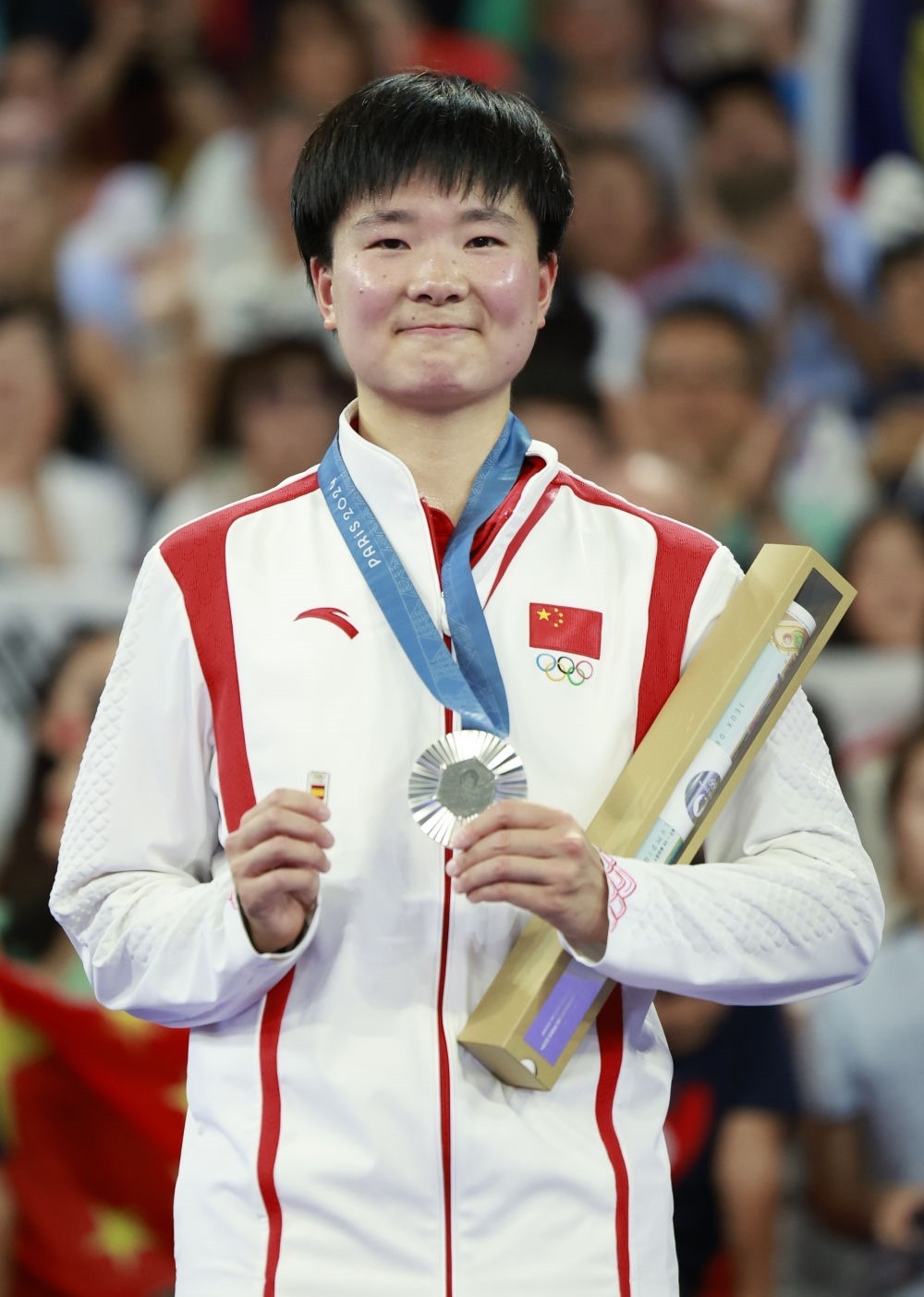 巴黎奧運會羽毛球女子單打亞軍、中國選手何冰嬌在頒獎儀式上一手握著銀牌，一手握著西班牙奧委會徽章（2024年8月5日攝）。新華社記者 任正來 攝