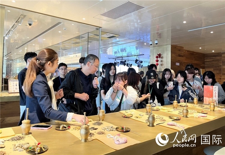 1. 日中友好協(xié)會(huì)青年代表團(tuán)一行學(xué)習(xí)中醫(yī)香囊制作工序。（人民網(wǎng)記者陳思 攝）