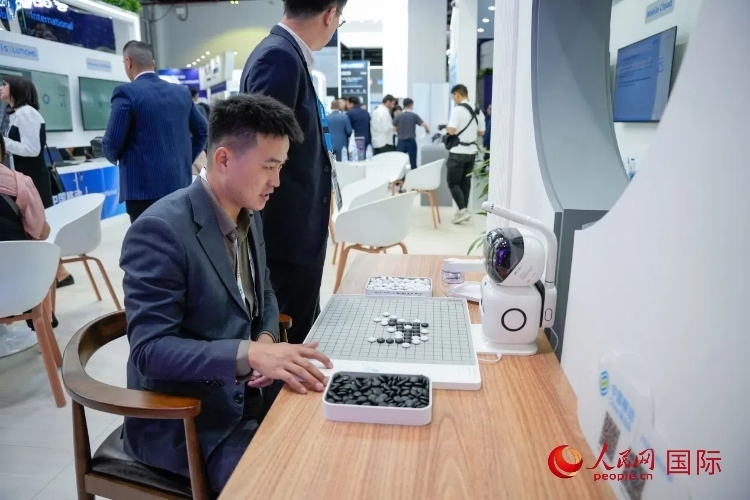 觀眾在中國(guó)移動(dòng)國(guó)際有限公司展臺(tái)體驗(yàn)智慧圍棋機(jī)器人。人民網(wǎng) 塔里克·易卜拉欣攝