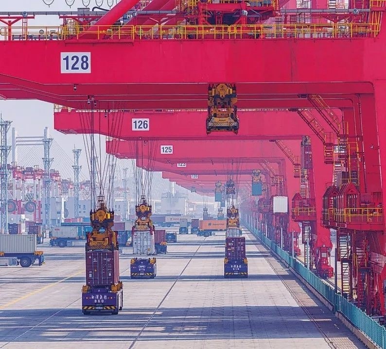 共建“一帶一路”國家在工作制度對接、技術標準協(xié)調(diào)、檢驗結果互認等方面強化合作、統(tǒng)一標準，貿(mào)易自由化便利化水平不斷提升。上海洋山港海關對接共建國家進出口貨物相關標準，推動通關一體化方式申報，提升通關效率。圖為無人駕駛的全自動導引車在洋山港穿梭往來，搬運集裝箱。王初 攝