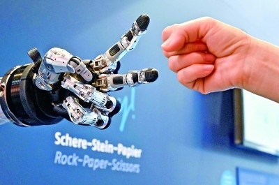 在德國(guó)漢諾威工博會(huì)上,參觀者與一款智能機(jī)器人進(jìn)行“石頭剪子布”游戲。新華社發(fā)