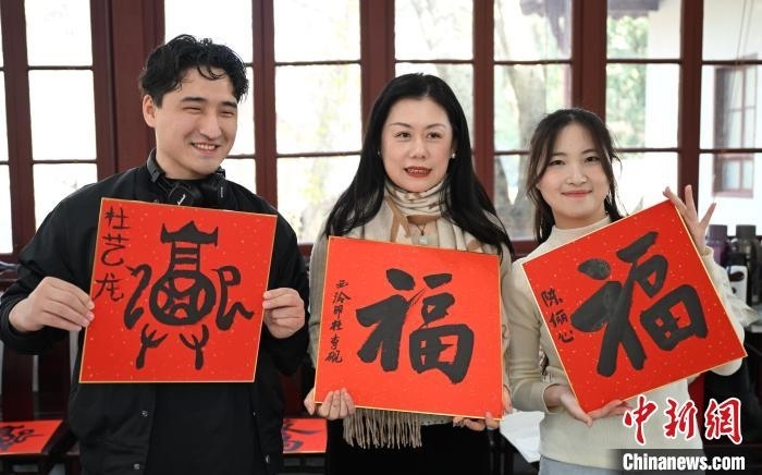 1月20日，外籍留學(xué)生和西泠印社社員李硯(中)展示各自創(chuàng)作的福貼。當日，來自巴西、馬來西亞、加納、哈薩克斯坦的外籍留學(xué)生在浙江杭州西泠印社體驗福貼、春聯(lián)和篆刻，感受古老的中國傳統(tǒng)文化。中新社記者 王剛 攝
