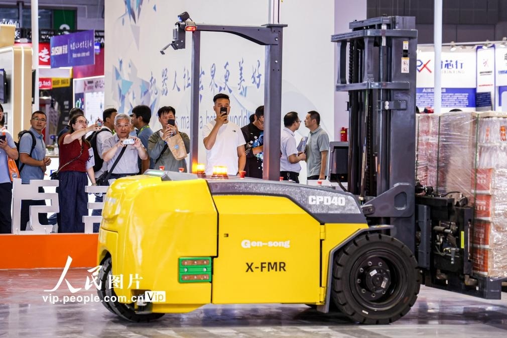 第24屆中國工博會現(xiàn)場，觀眾觀看叉取機器人作業(yè)演示。王初攝（人民圖片網(wǎng)）