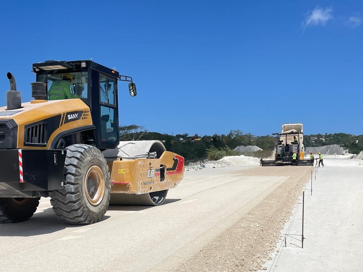 圖為中企承建的牙買加蒙特哥貝繞城路項(xiàng)目基層試驗(yàn)段正在進(jìn)行攤鋪和碾壓施工，相關(guān)施工工作已于日前順利完成。中國港灣美洲區(qū)域公司供圖