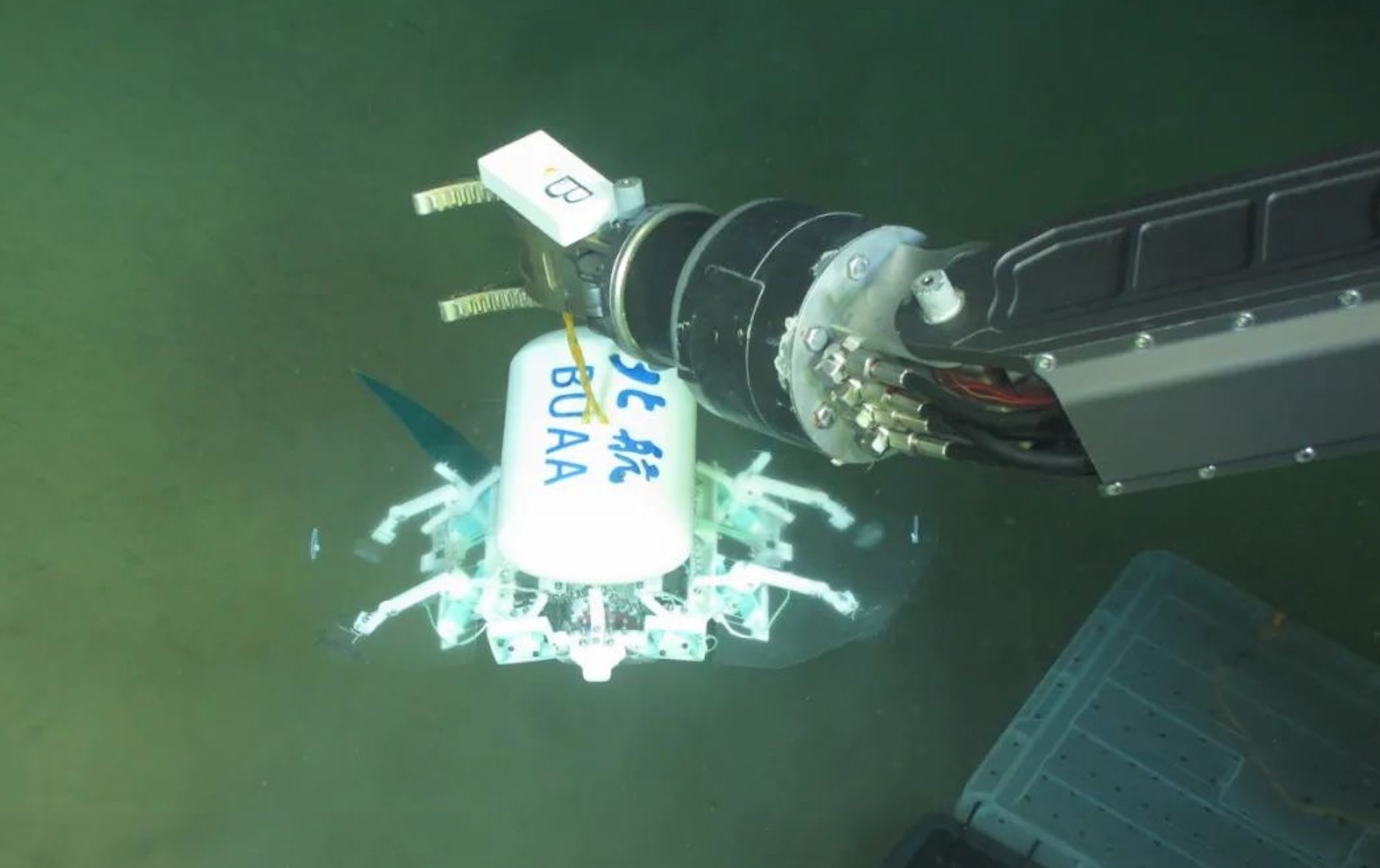 科研人員利用機械臂將北航深海小型機器人投于馬里亞納海溝。校方供圖