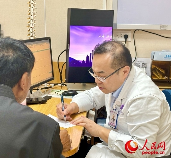 路桂軍接診時(shí)為患者寫下用藥提示。人民網(wǎng)記者 金慧慧攝