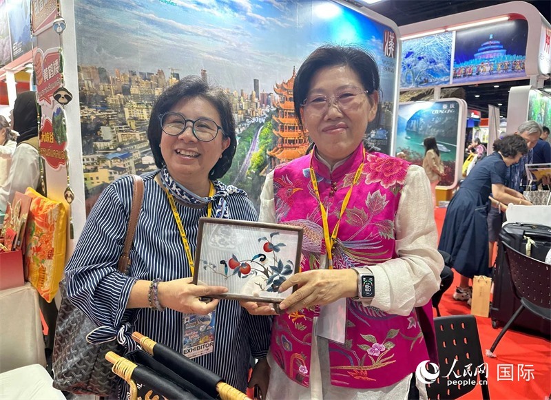 中國“大冶刺繡”傳承人劉小紅（右）參加泰國國際旅游展，向觀眾介紹中國非遺刺繡針法。人民網(wǎng)記者 簡承淵攝