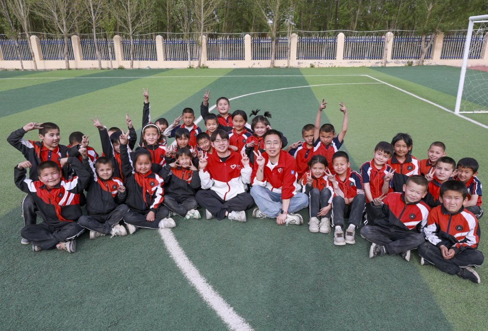4月23日，在新疆克州阿圖什市哈拉峻鄉(xiāng)謝依特小學(xué)，支教教師王俊文（中左）、李軻凡（中右）和學(xué)生在一起。