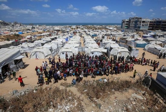 5月28日，人們在加沙城西部的沙提難民營等待領(lǐng)取救助食物。新華社發(fā)（里澤克·阿卜杜勒賈瓦德攝）